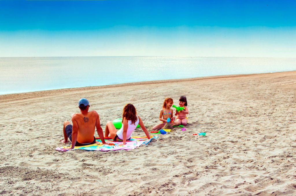 Happy family enjoying sunny beach at Rosolina Mare – perfect seaside vacation spot