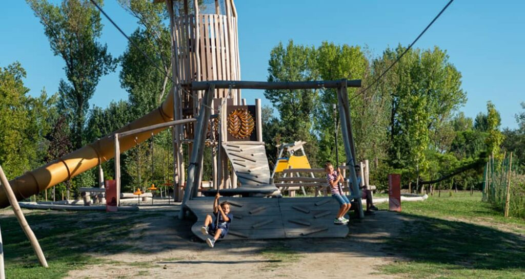 Kinder spielen auf Schaukeln und Spielgeräten in Albarellaland