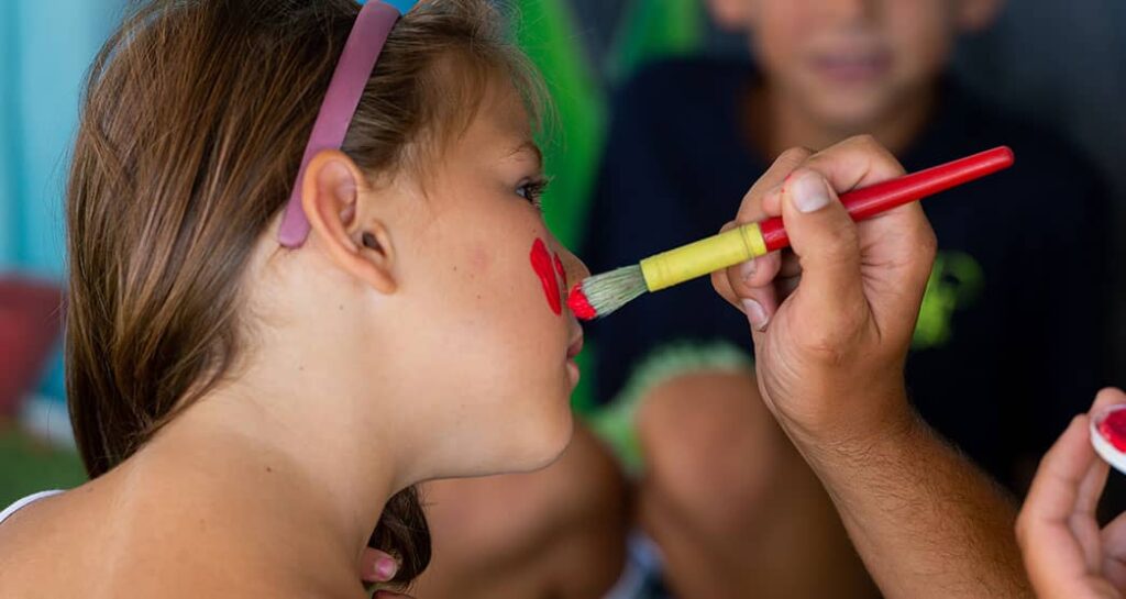 Kinderschminken, durchgeführt von einem Animateur auf dem Gesicht eines Mädchens